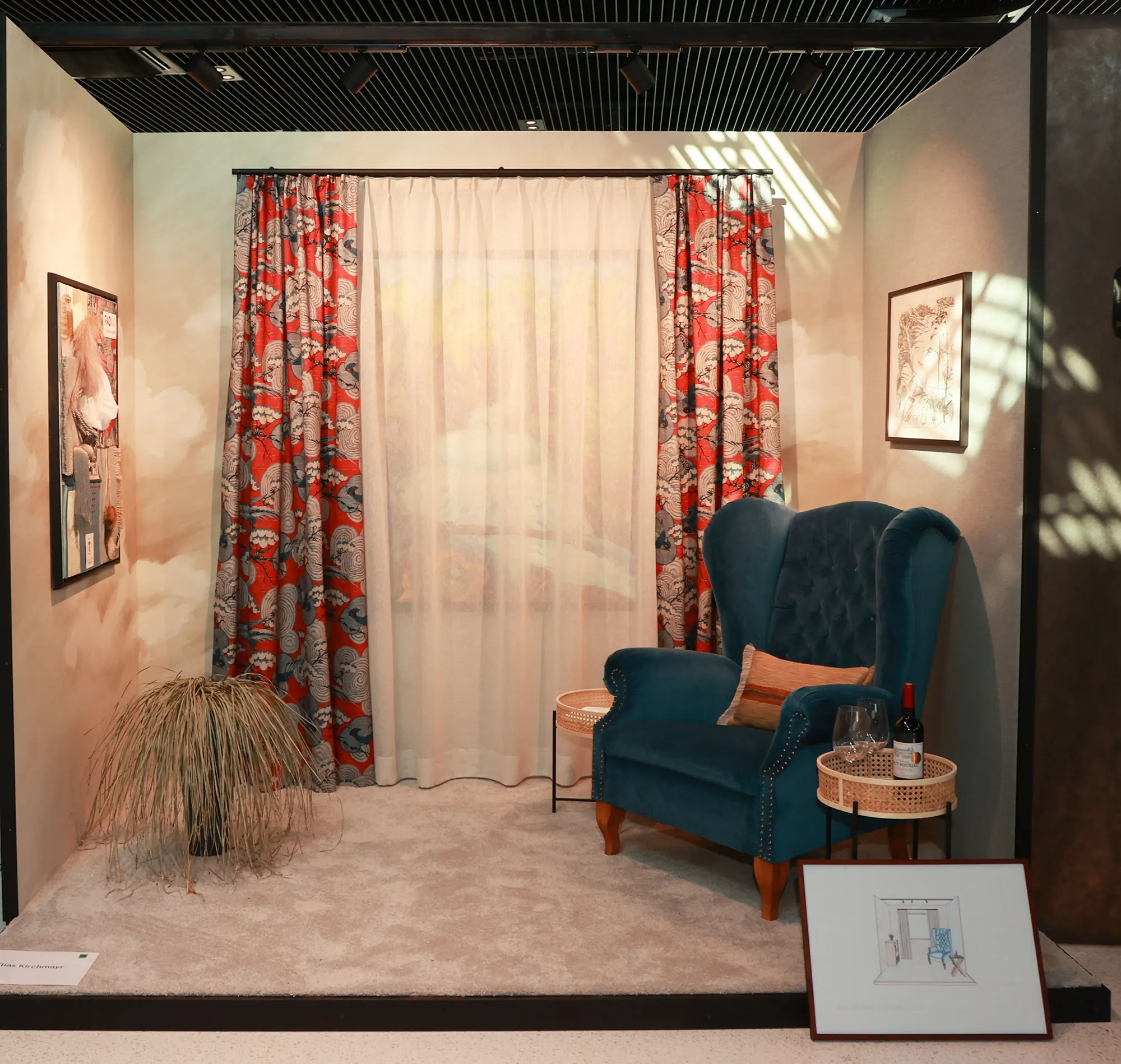 In einer gemütlichen Ecke stehen ein blauer Sessel, rot-weiß gemusterte Vorhänge und eine sanfte Beleuchtung. Eine gerahmte Skizze und eine Weinflasche verleihen ihr einen einladenden Touch.